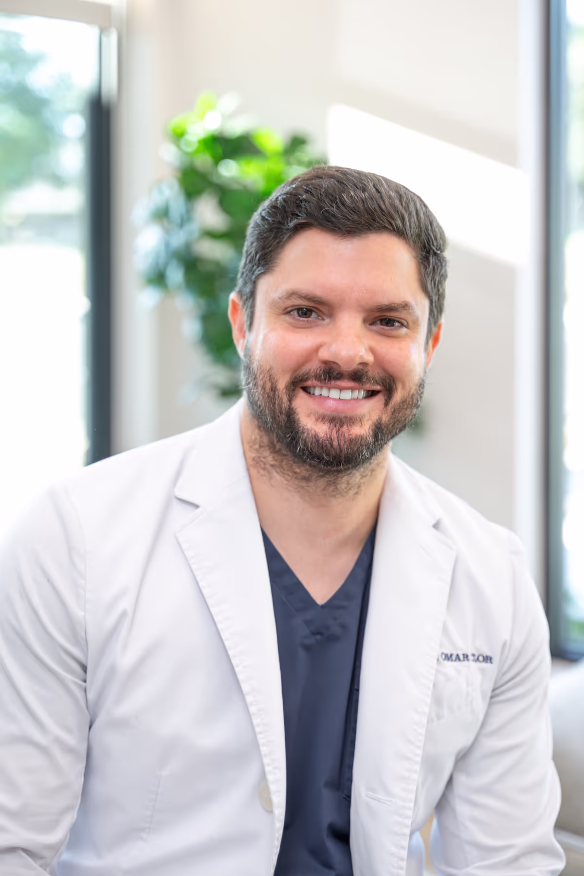 Dr. Clor in a white lab coat smiles at the camera.